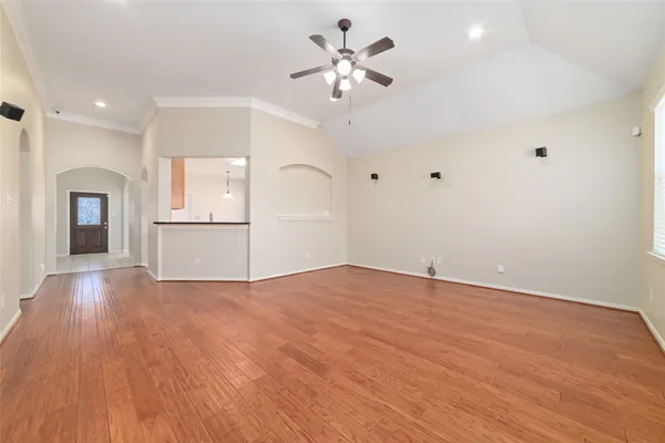 a view of empty room with wooden floor and ceiling fan