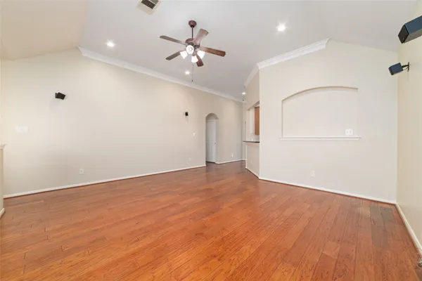 a view of an empty room with wooden floor and chandelier