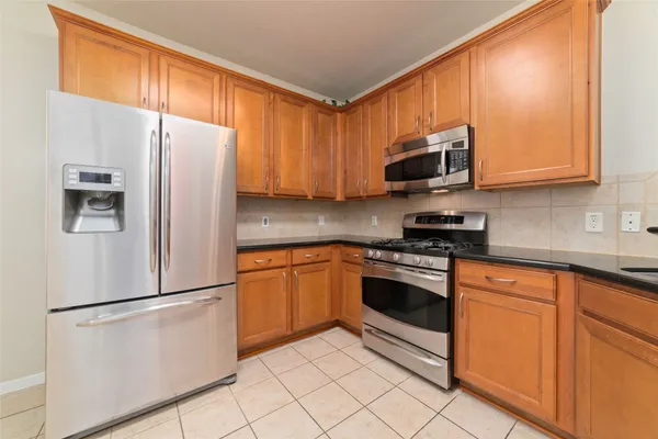 a kitchen with stainless steel appliances granite countertop a refrigerator stove top oven and sink