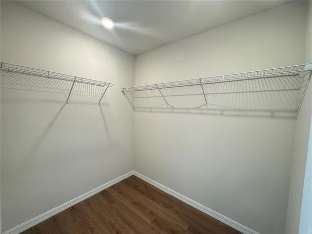 a view of an empty room with wooden floor and closet