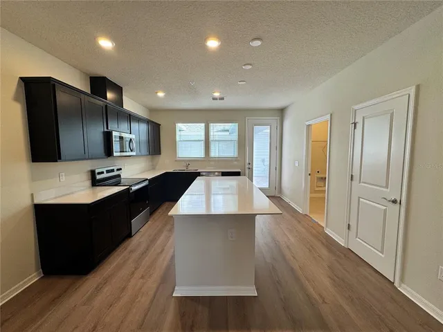 a large kitchen with stainless steel appliances wooden floors and wooden cabinets