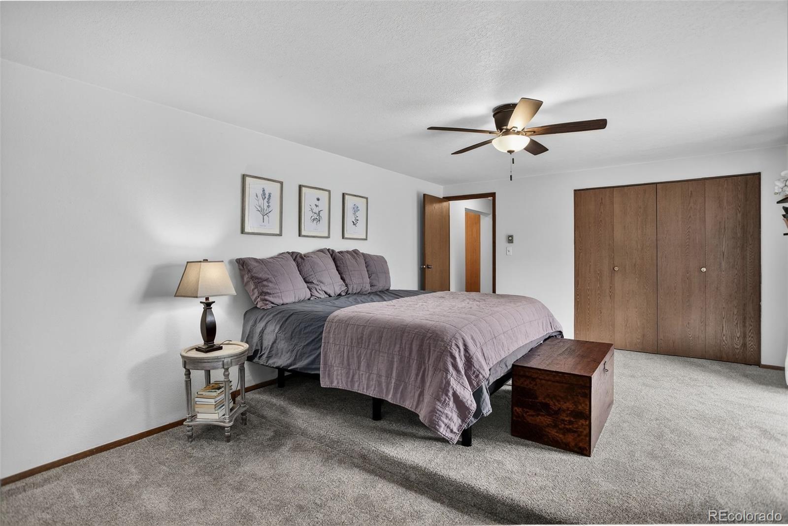 31911 Warrens Road Golden, CO 80403 - Photo 15 of 42 a spacious bedroom with a bed and a chandelier