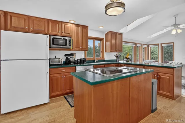 a view of a kitchen with kitchen island a large window cabinets a sink and stainless steel appliances