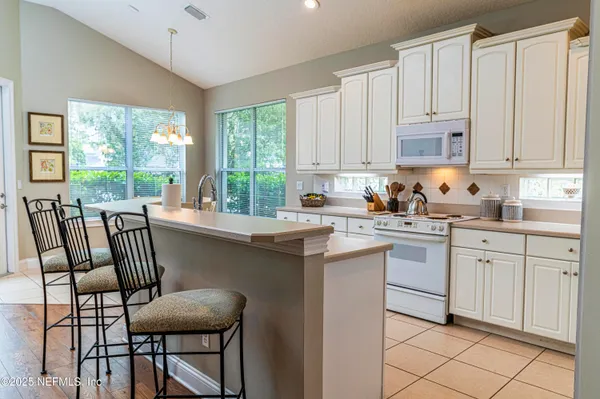 a kitchen with a stove a sink and white cabinets