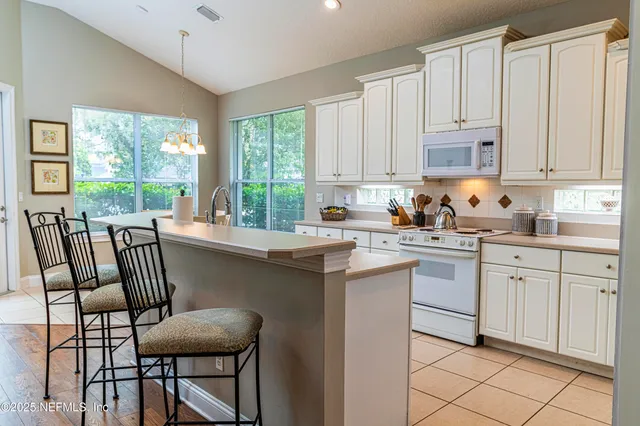 a kitchen with a stove a sink and white cabinets