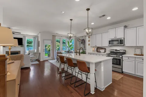 a kitchen with stainless steel appliances kitchen island wooden floors and white cabinets