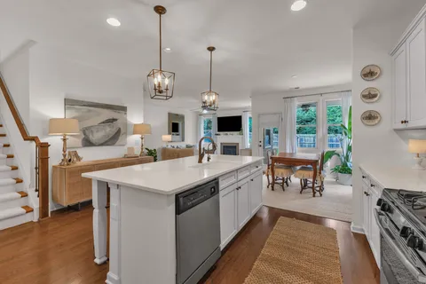 a kitchen with stainless steel appliances granite countertop a stove oven a sink dishwasher and a dining table with wooden floor