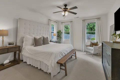 a spacious bedroom with a bed couch and a flat tv screen