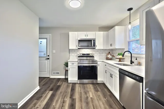 a kitchen with granite countertop a stove top oven a sink dishwasher and a refrigerator with wooden floor