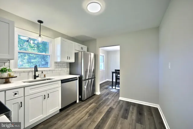 a kitchen with a sink dishwasher a stove and white cabinets with wooden floor