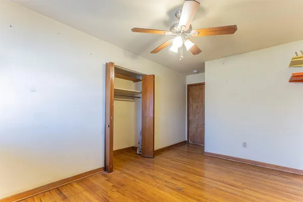 an empty room with wooden floor chandelier fan and windows