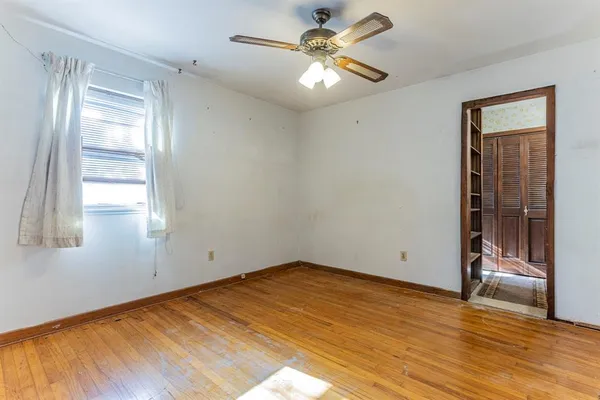 a view of an empty room with window and wooden floor