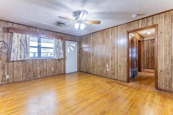 a view of an empty room with cabinet mirror and a kitchen view