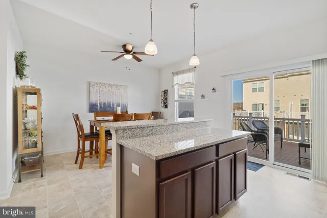 a kitchen with stainless steel appliances granite countertop a stove top oven a sink a dining table and chairs with wooden floor