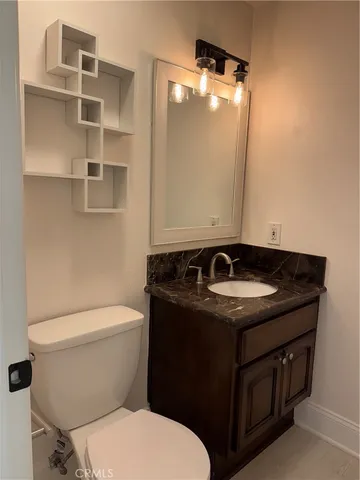 a bathroom with a granite countertop sink and a toilet
