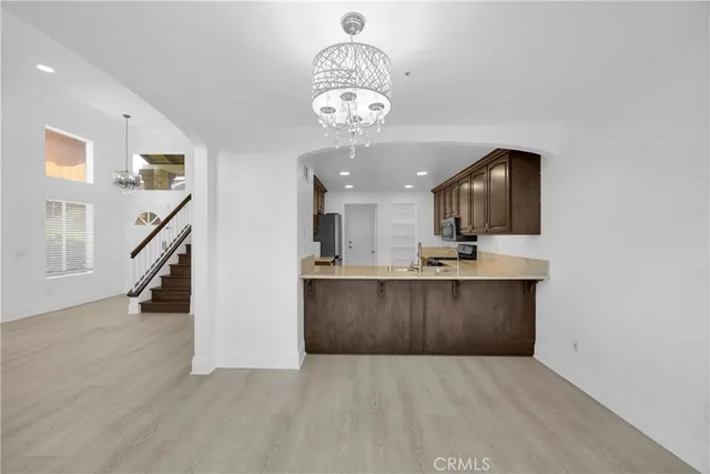 a view of a hallway with wooden floor and a kitchen