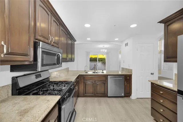 a kitchen with stainless steel appliances granite countertop a stove a sink and a microwave