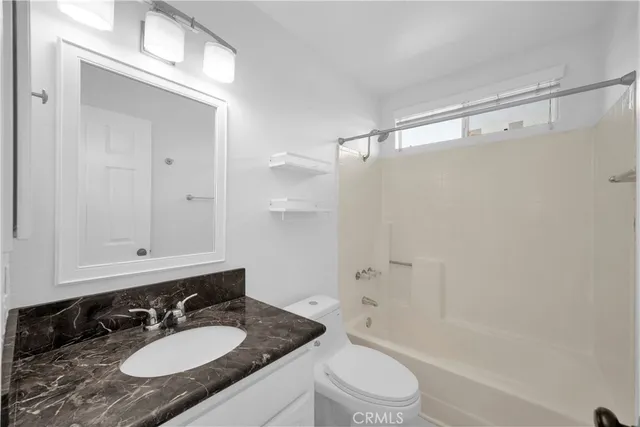a bathroom with a granite countertop sink a toilet and shower