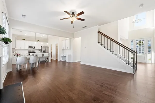 a view of a dining room and livingroom with furniture wooden floor a ceiling fan and a rug