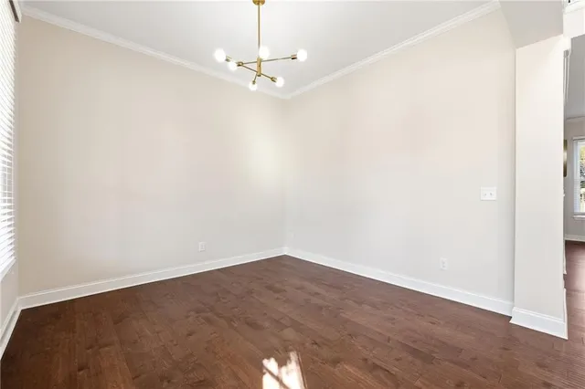 an empty room with wooden floor and chandelier
