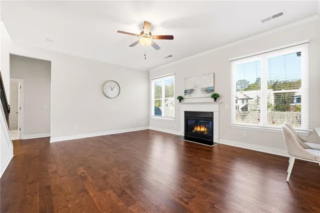 a view of an empty room with wooden floor fireplace and a window