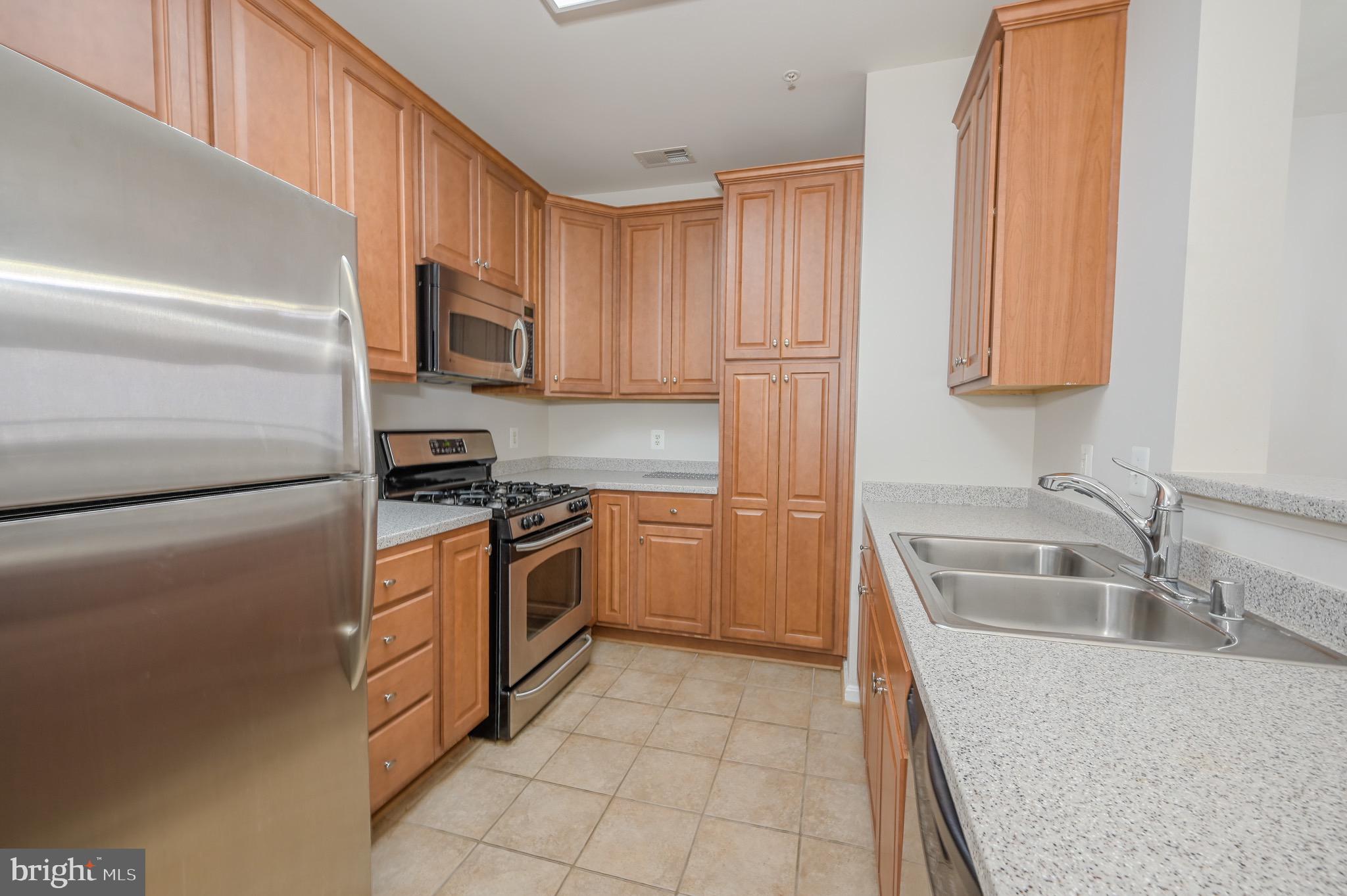 21216 McFadden Square, Unit 206 Sterling, VA 20165 - Photo 8 of 11 a kitchen with stainless steel appliances granite countertop a sink and a refrigerator