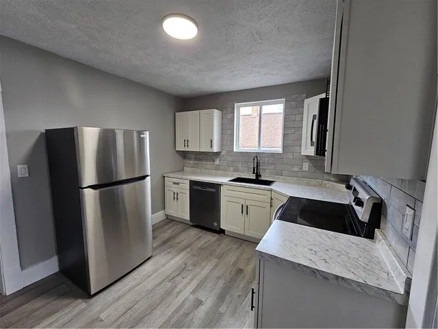 a kitchen with a refrigerator sink and cabinets