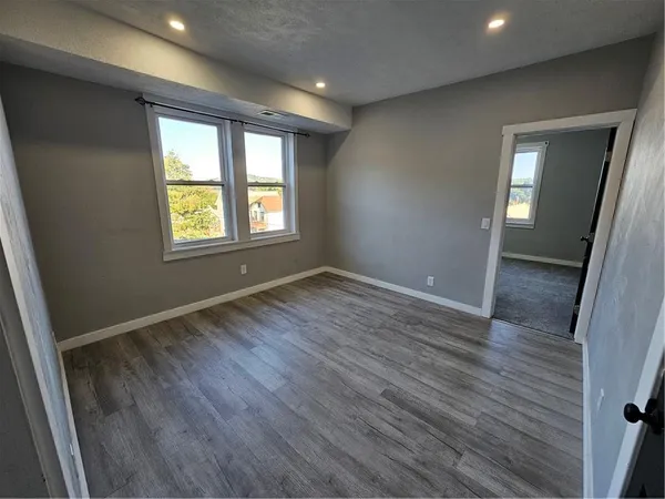an empty room with wooden floor and windows