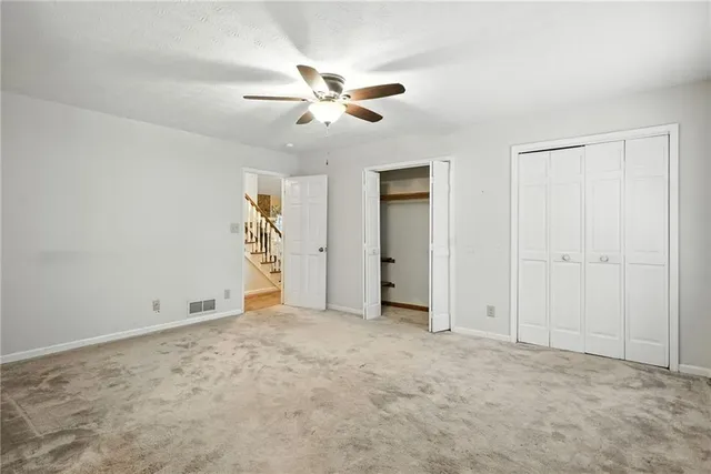 an empty room with closet and a chandelier fan