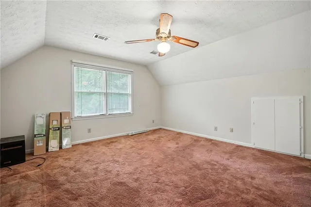 an empty room with chandelier fan and windows