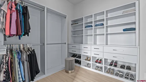 a view of walk in closet with clothes and shoes