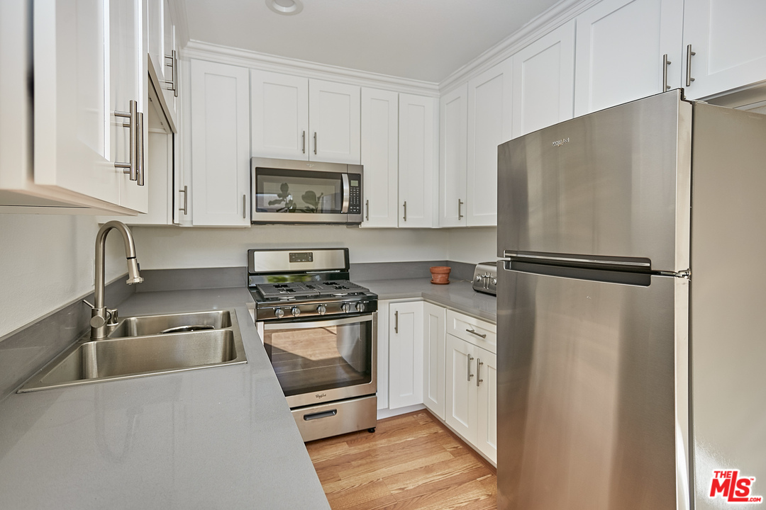 433 Cottage Home Street, Unit 4 Los Angeles, CA 90012 - Photo 5 of 13 a kitchen with white cabinets and stainless steel appliances