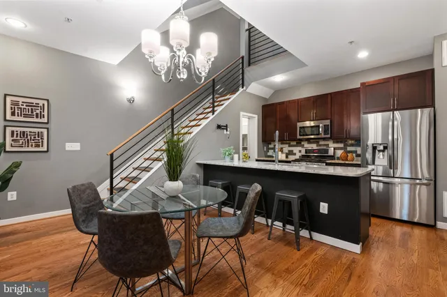 a kitchen with stainless steel appliances granite countertop a refrigerator a stove a sink dishwasher a dining table and chairs with wooden floor