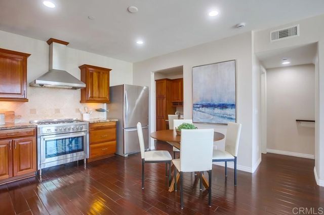 a kitchen with stainless steel appliances granite countertop wooden floor a stove a sink a dining table and chairs with wooden floor