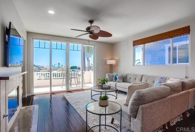 a living room with furniture a ceiling fan and a floor to ceiling window
