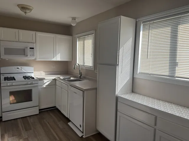 a kitchen with white cabinets and white appliances