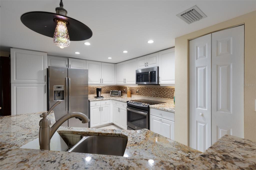 9341 Blind Pass Road St. Pete Beach, FL 33706 - Photo 9 of 44 a kitchen with stainless steel appliances kitchen island granite countertop a sink a refrigerator and a stove