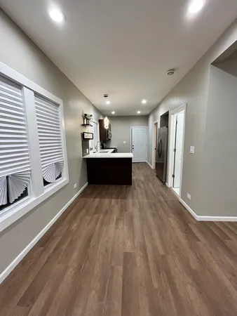 a living room with stainless steel appliances kitchen island granite countertop a refrigerator stove a sink and dishwasher with wooden floor