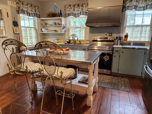 a kitchen with stainless steel appliances a table chairs and a wooden floors