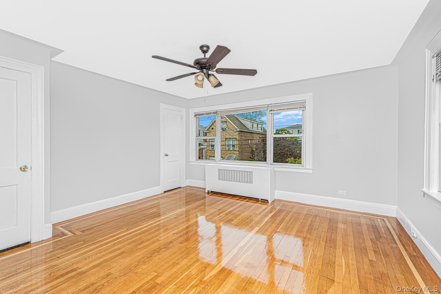 1616 Library Avenue Bronx, NY 10465 - Photo 12 of 20 Empty room featuring light wood-style floors, radiator heating unit, and a ceiling fan