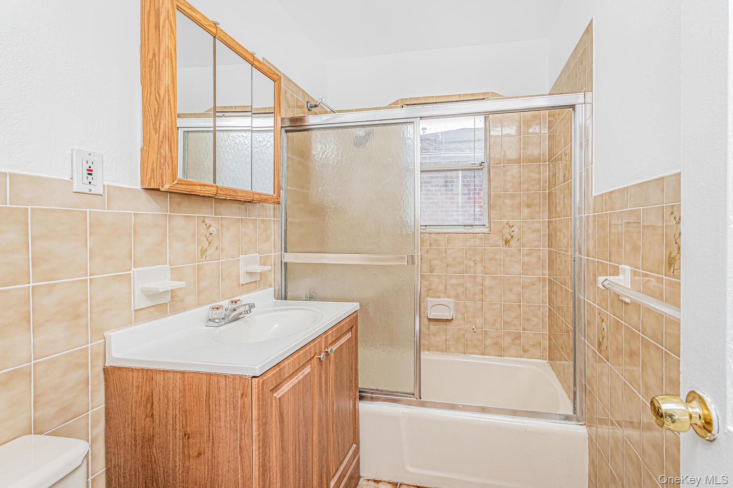 1616 Library Avenue Bronx, NY 10465 - Photo 18 of 20 Bathroom with tile walls, bath / shower combo with glass door, and vanity