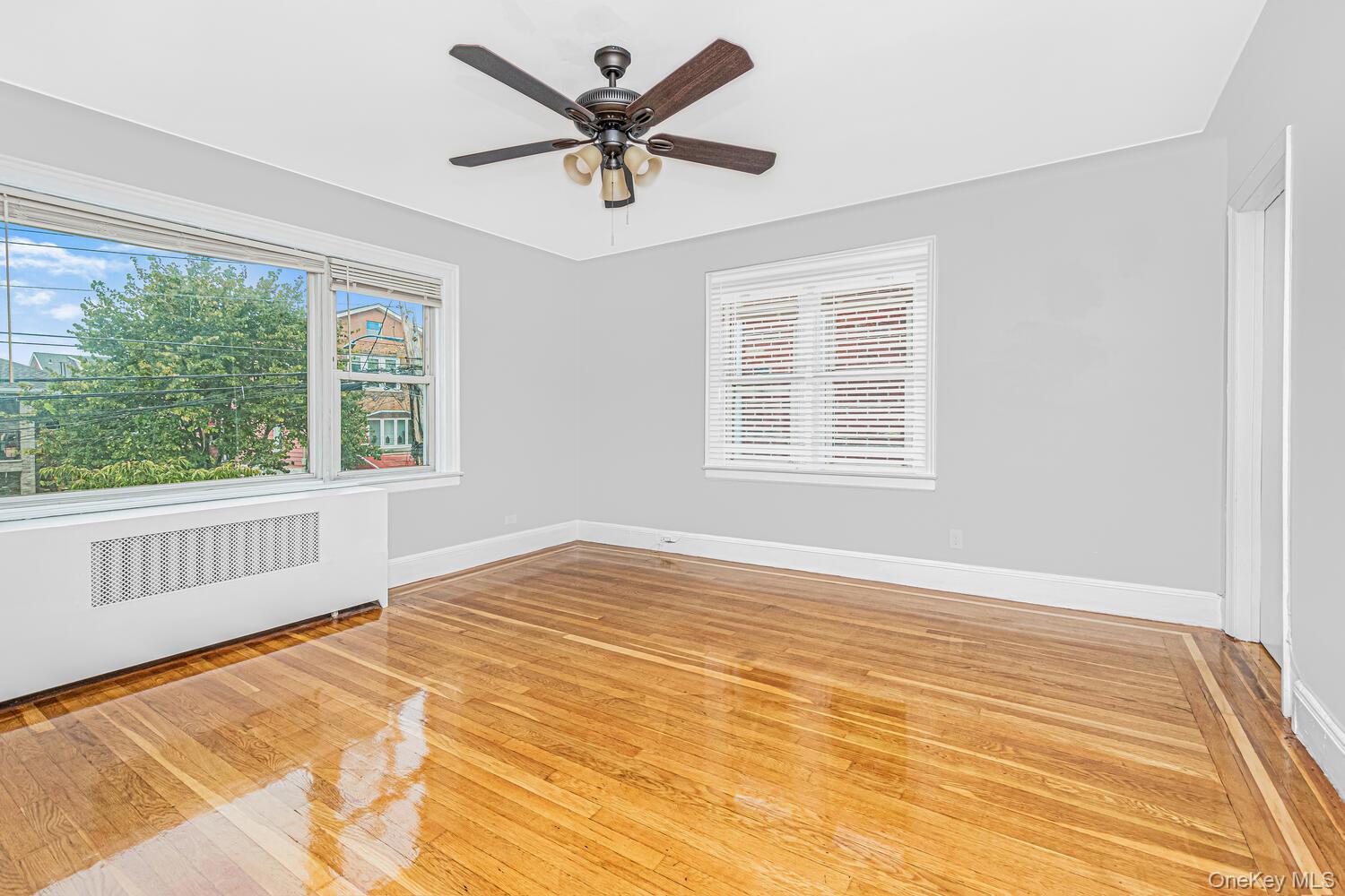 1616 Library Avenue Bronx, NY 10465 - Photo 4 of 20 Spare room featuring light wood-type flooring, radiator heating unit, and ceiling fan