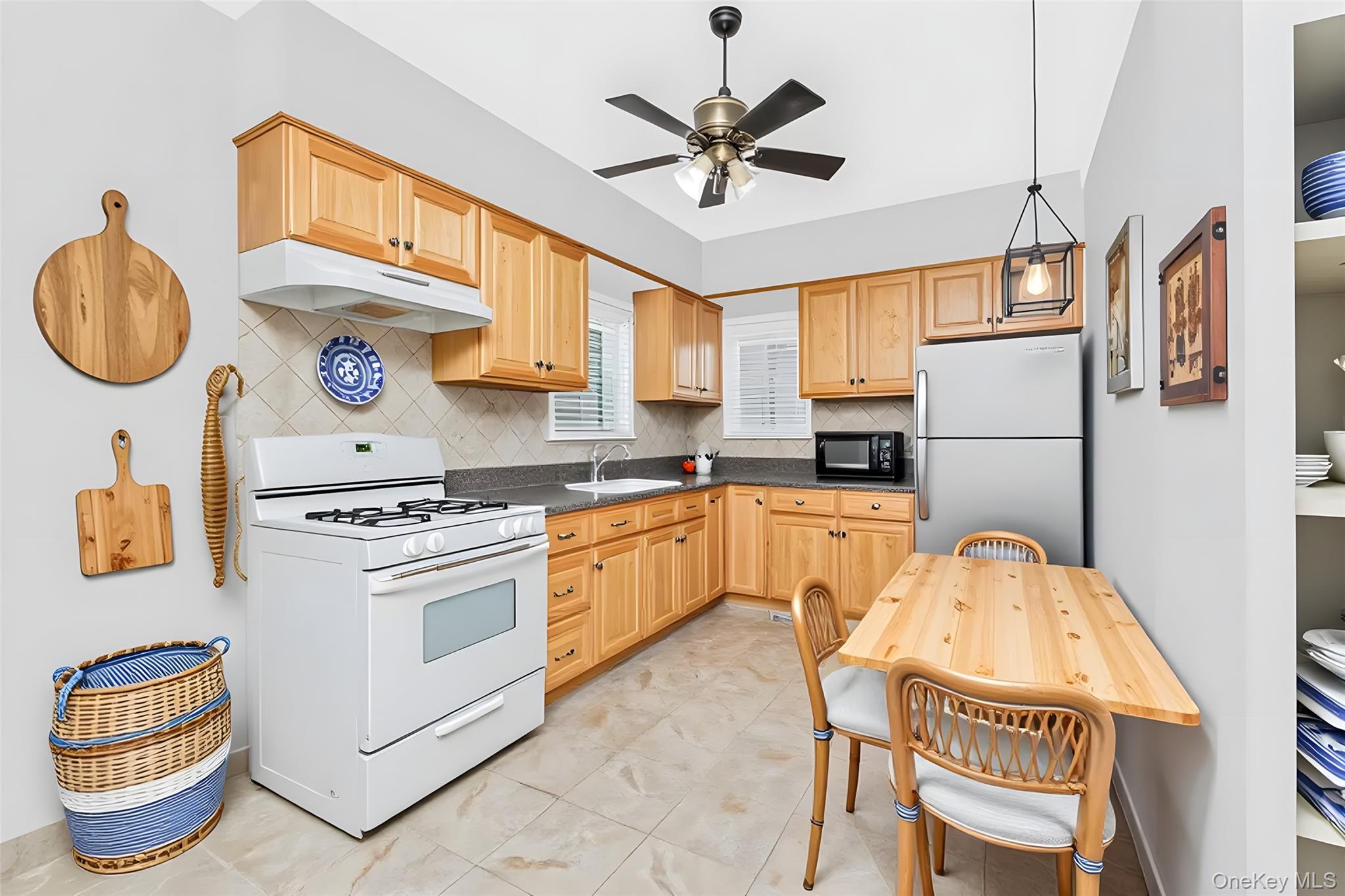 1616 Library Avenue Bronx, NY 10465 - Photo 9 of 20 Kitchen featuring white gas range oven, backsplash, freestanding refrigerator, under cabinet range hood, and dark countertops