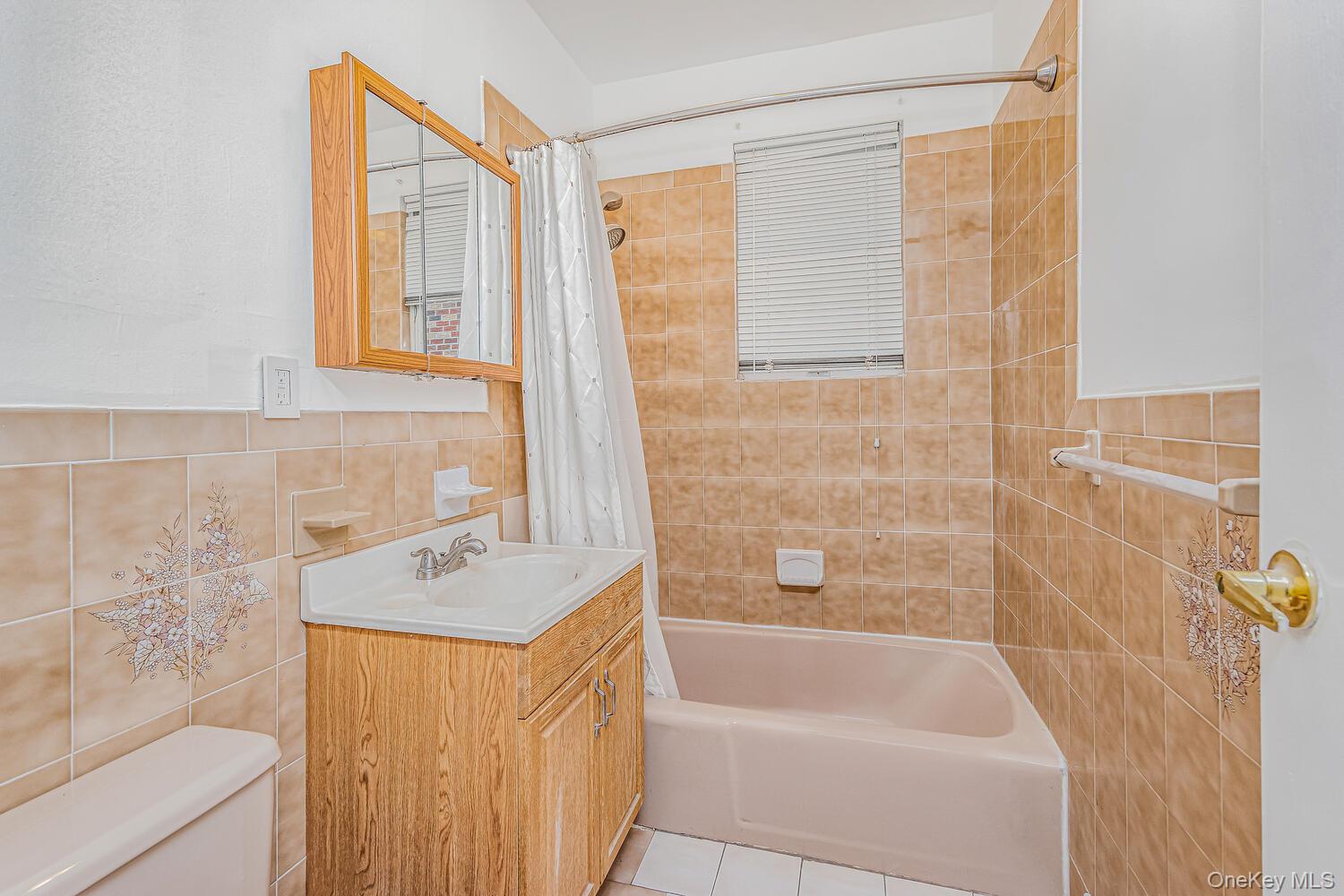 1616 Library Avenue Bronx, NY 10465 - Photo 10 of 20 Bathroom featuring tile walls, shower / bath combination with curtain, vanity, and light tile patterned floors