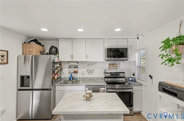 a kitchen with stainless steel appliances a refrigerator a stove a sink dishwasher a dining table and chairs with wooden floor