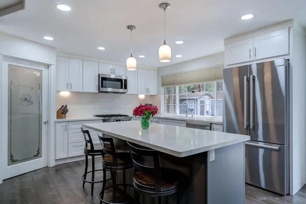 a kitchen with stainless steel appliances granite countertop a table chairs refrigerator and microwave