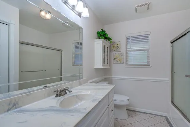 a bathroom with a granite countertop toilet a sink and a mirror