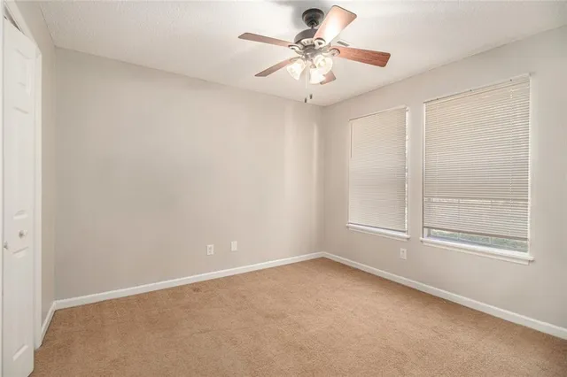 an empty room with a chandelier fan and windows