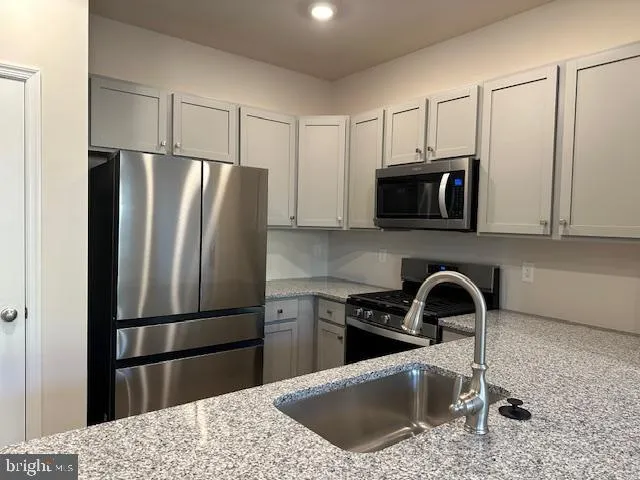 a kitchen with stainless steel appliances granite countertop a refrigerator a sink a stove a microwave and cabinets