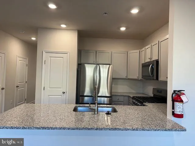 a kitchen with kitchen island granite countertop a sink and refrigerator